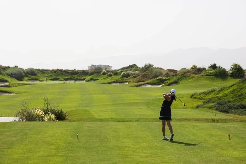 Een golfer op de glooiende fairway van Al Mouj Golf